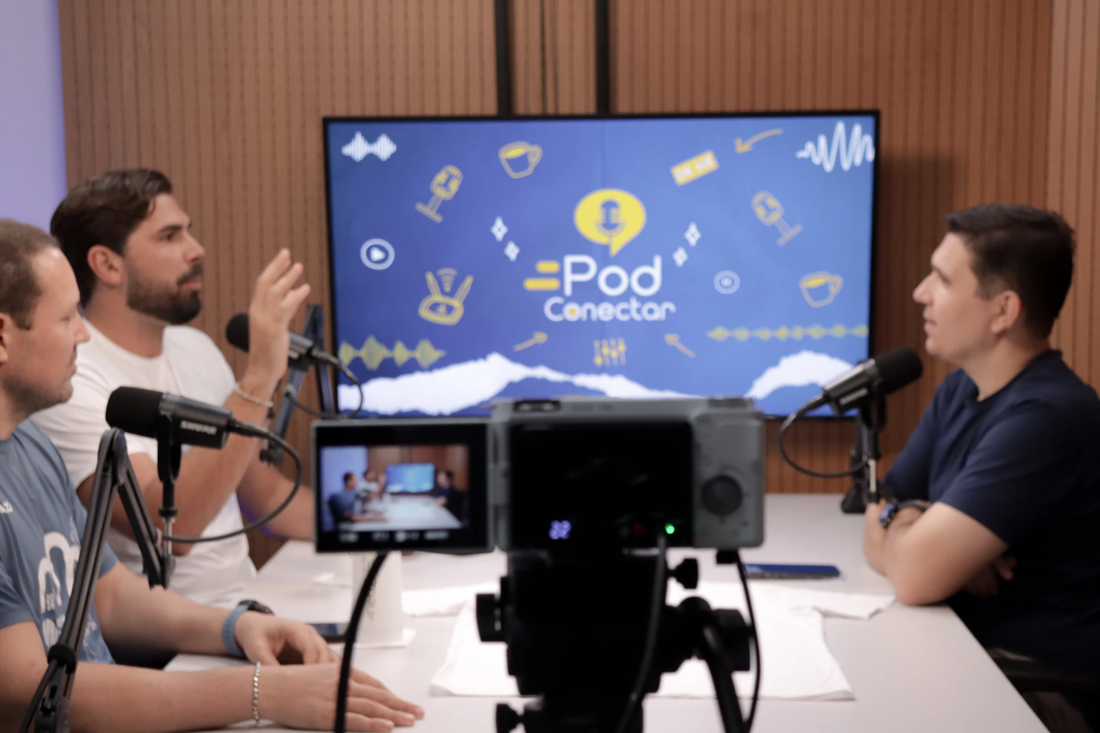 Organizador do BT200 Aracaju gesticula enquanto conta os bastidores do torneio no PodConectar #86, com a câmera de gravação em primeiro plano