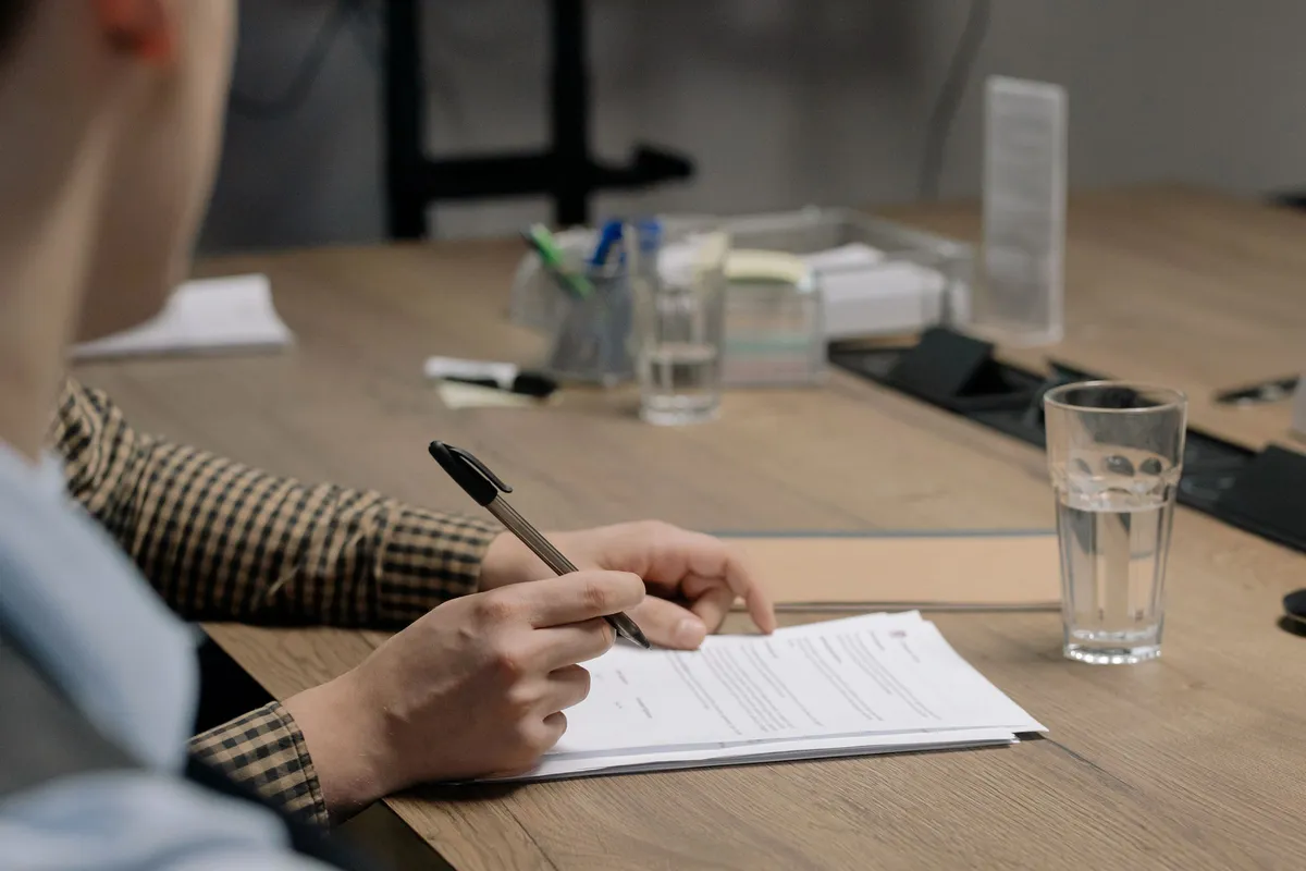 Pessoa assinando documentos sobre uma mesa de escritório, etapa em que o consentimento para o tratamento de dados pessoais é registrado