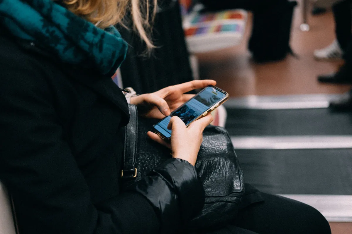 Mulher usando o celular durante um deslocamento, momento em que dados de navegação e interação podem ser coletados sob as regras da LGPD