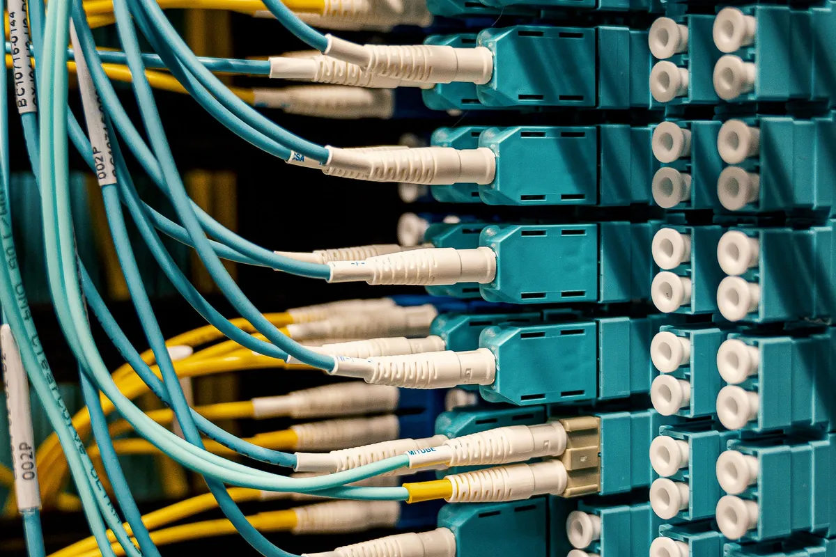 Cabos de fibra óptica conectados a um switch de rede, o caminho físico que os dados percorrem e que influencia o ping alto nos jogos