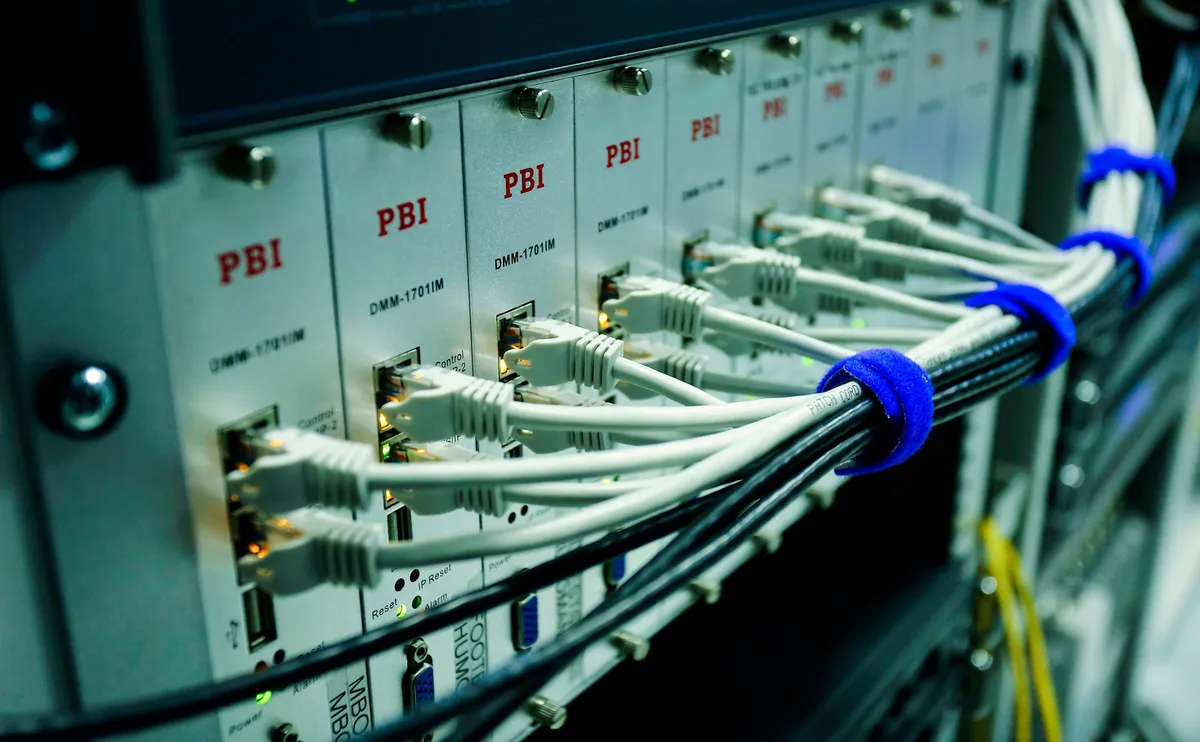 Cabos de rede conectados a um switch, a infraestrutura das rotas e interconexões que levam os dados do jogo até o servidor