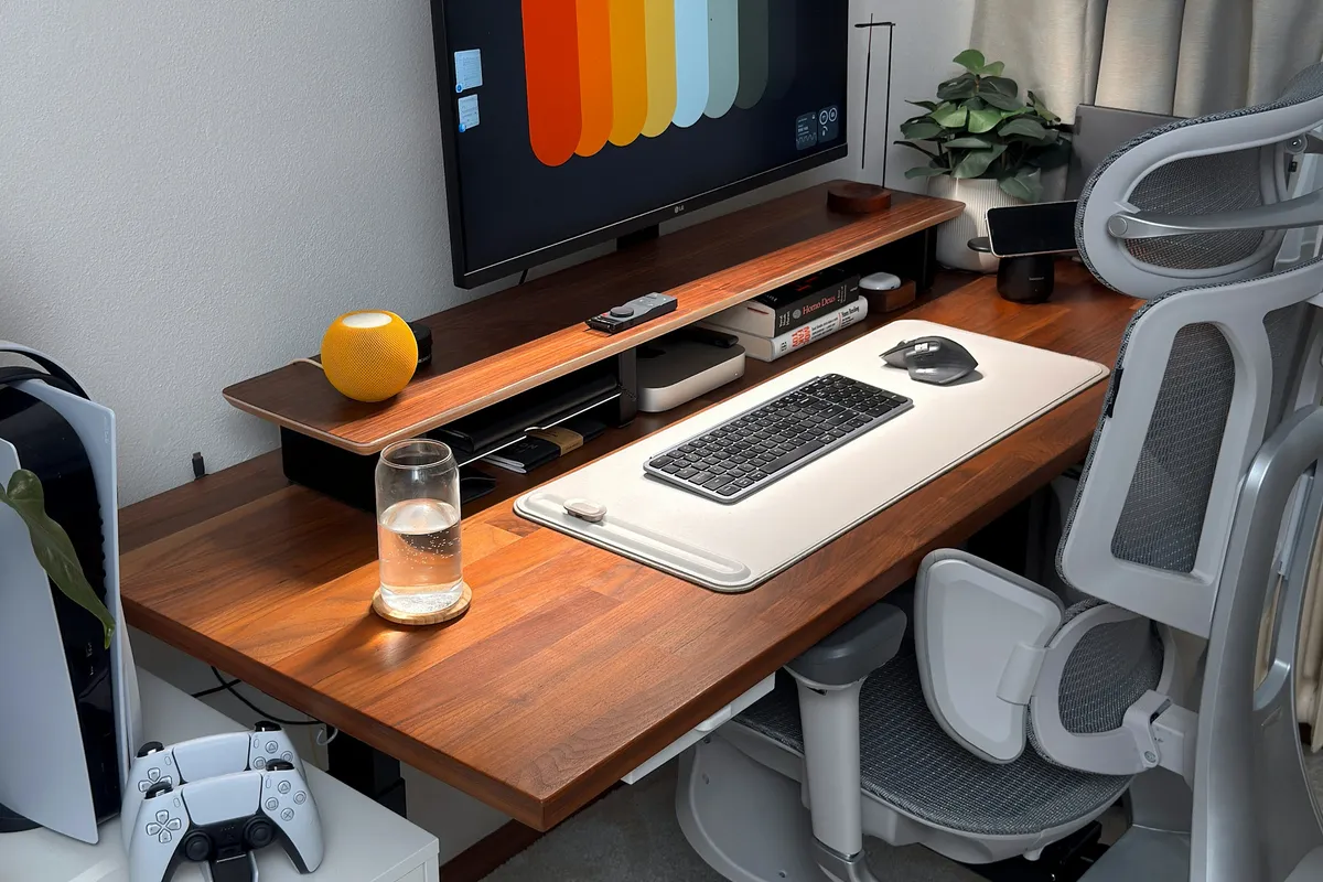 Setup de mesa organizado com computador e console de videogame, ambiente ideal para conectar o aparelho direto no roteador por cabo