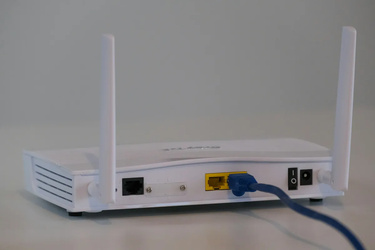 Roteador branco com cabo de rede conectado, a ligação por cabo usada no modo Access Point e no backhaul cabeado do mesh
