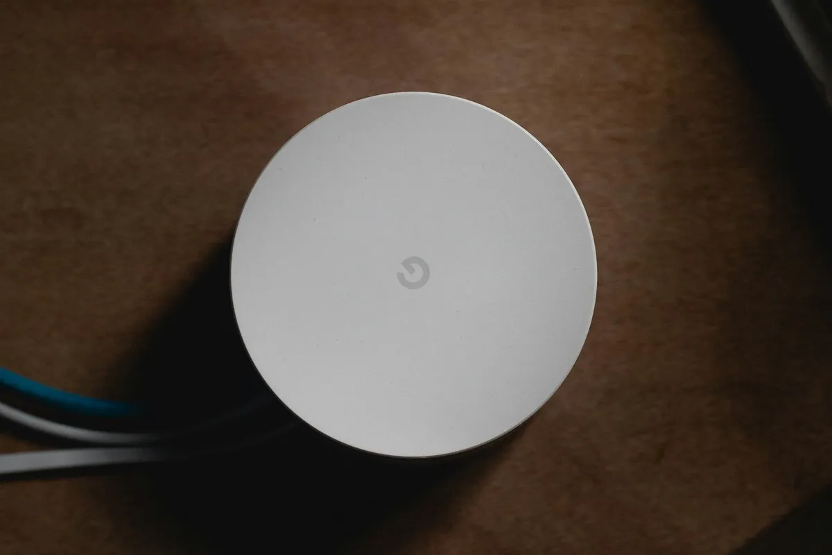 Aparelho de Wi-Fi mesh branco sobre uma mesa de madeira na sala, exemplo de nó do sistema mesh em área aberta