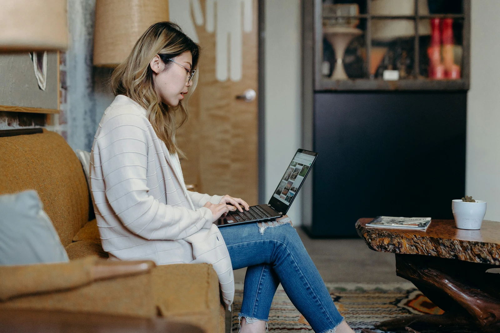 Mulher navegando na internet com o notebook no colo, sentada no sofá de casa, depois de recusar os cookies não necessários