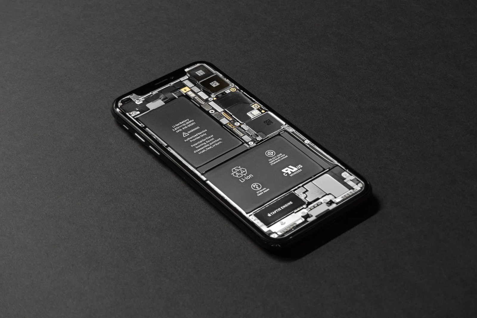 Smartphone com a parte interna à mostra, com placa e bateria, sobre uma superfície escura: é no hardware do aparelho que fica o suporte a cada padrão de Wi-Fi